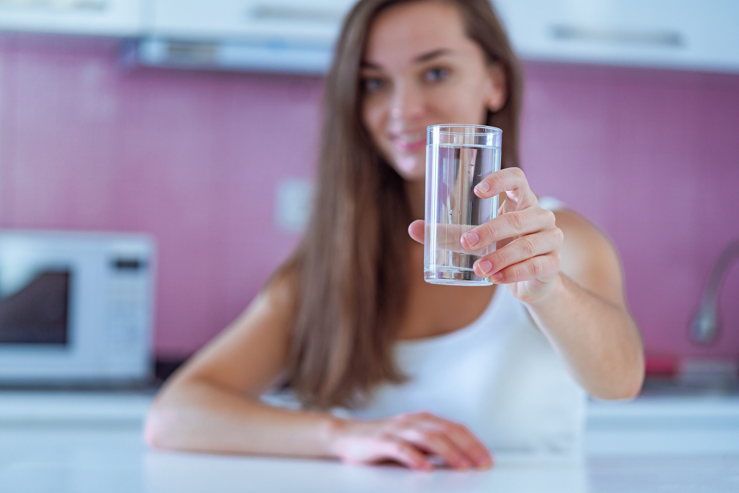 Temiz arıtılmış su bardağı elinde tutan mutlu içme kadın