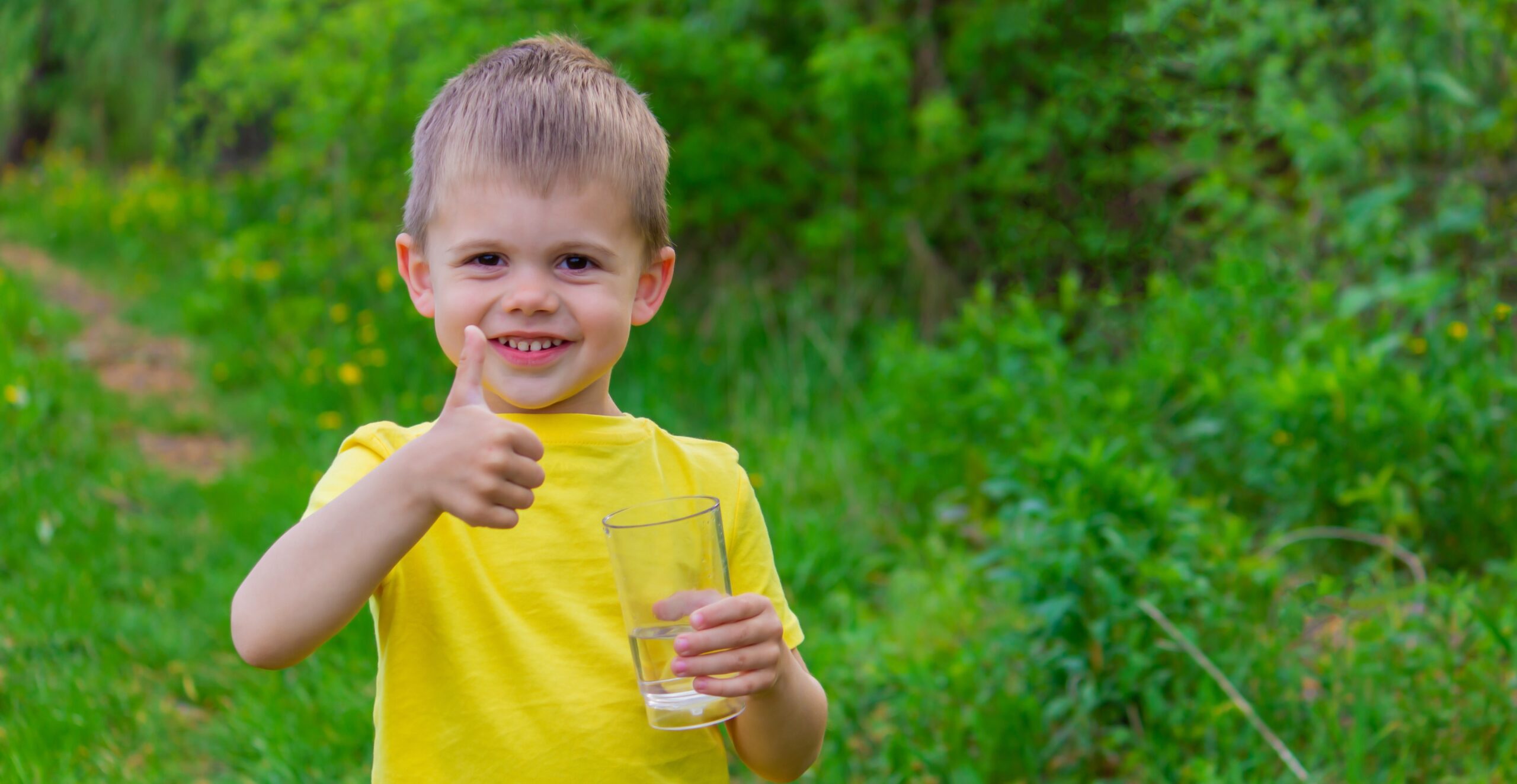 küçük erkek çocuk parkta bir bardakla içme suyu.