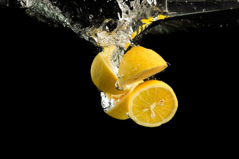 Siyah arkaplanda taze sarı limonun suya düşmesi